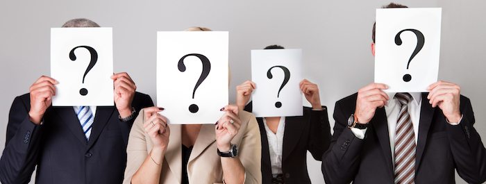 Group of unidentifiable business people hiding under question marks